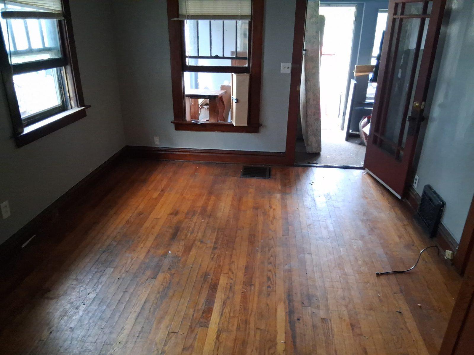 Cleared room inside the house with original hardwood floor exposed and nothing left on it