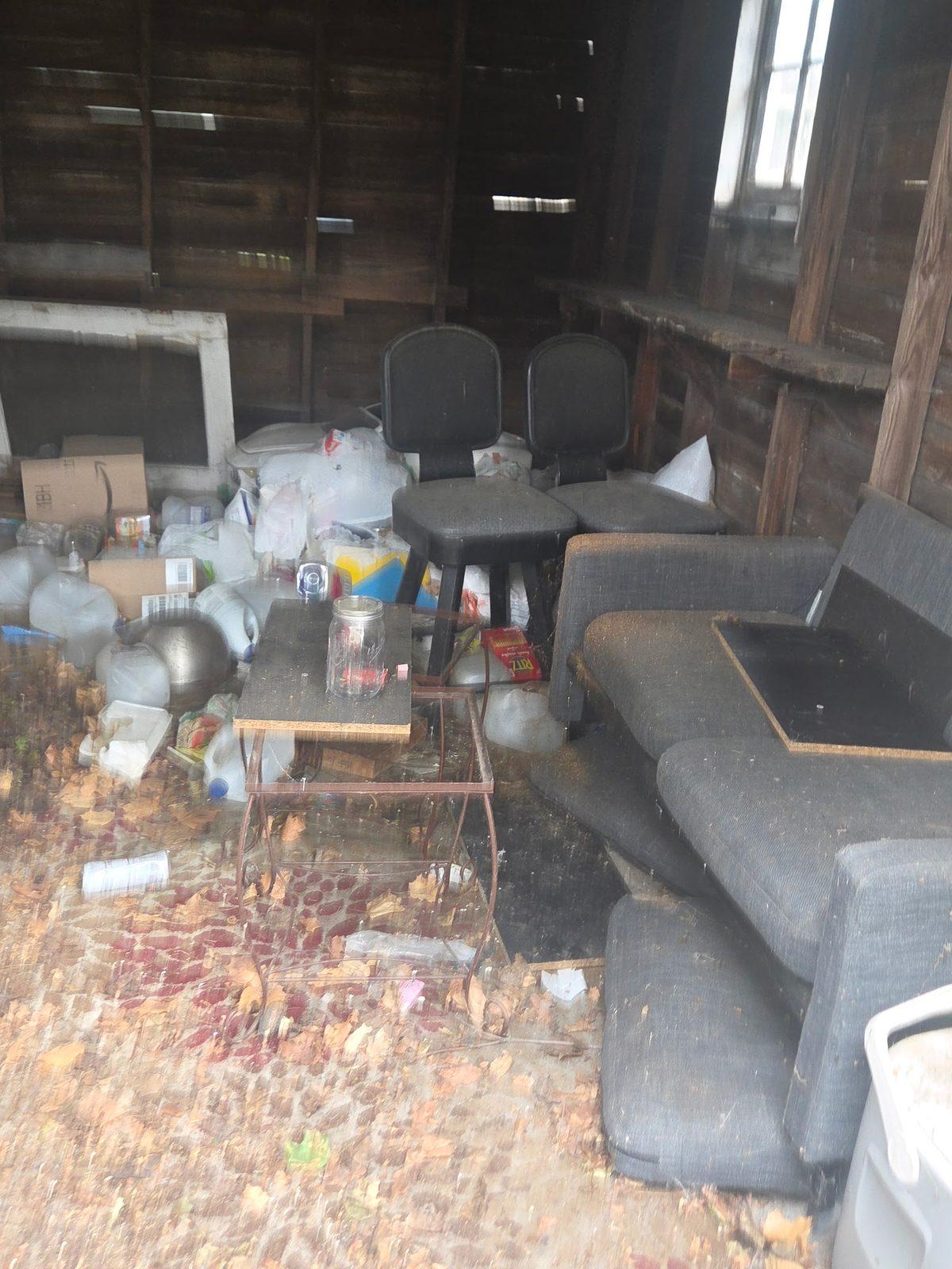Interior of a detached timber garage packed with discarded furniture and household refuse
