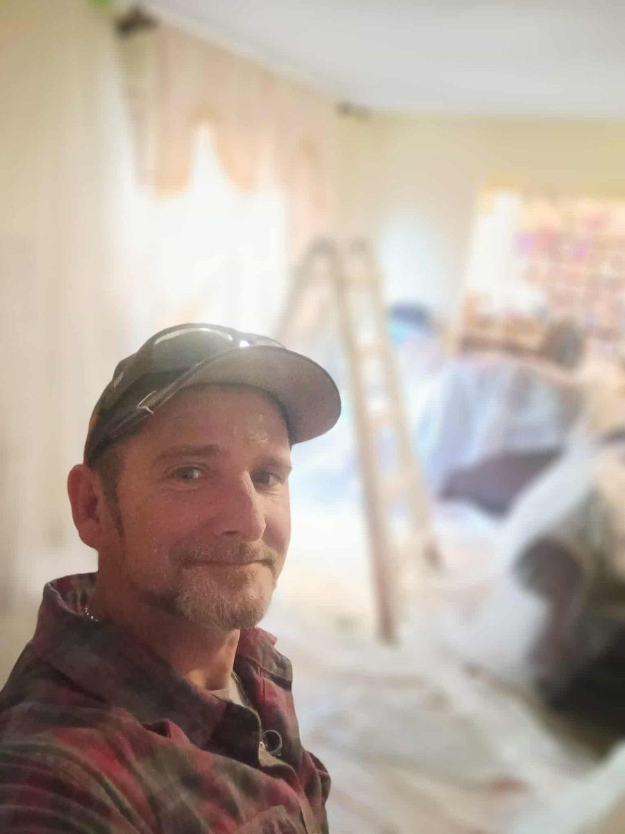 Jason White on a job site, with a step ladder and dust sheets behind him