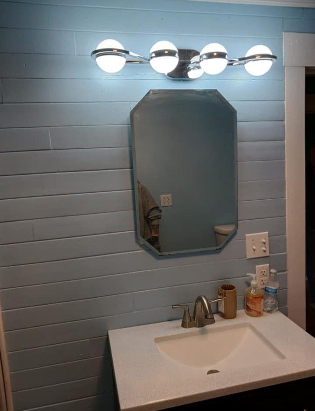 Finished bathroom with grey shiplap walls, a framed mirror and a new vanity top