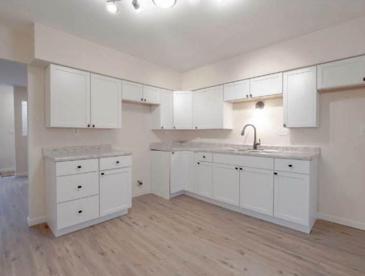 The finished kitchen with white shaker cabinets, new worktops and new flooring