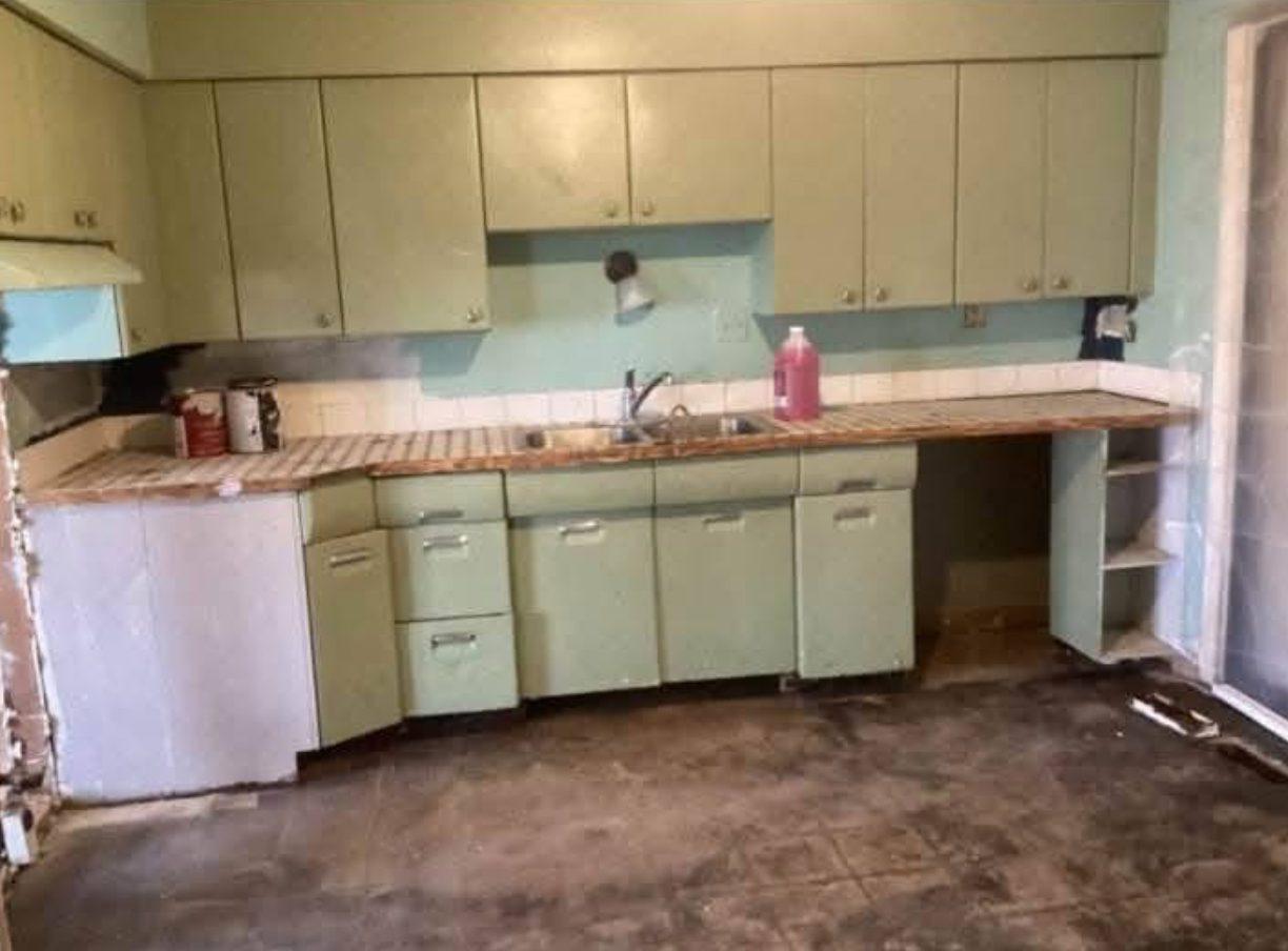 Original kitchen with green metal cabinets, a tiled worktop and a stripped floor