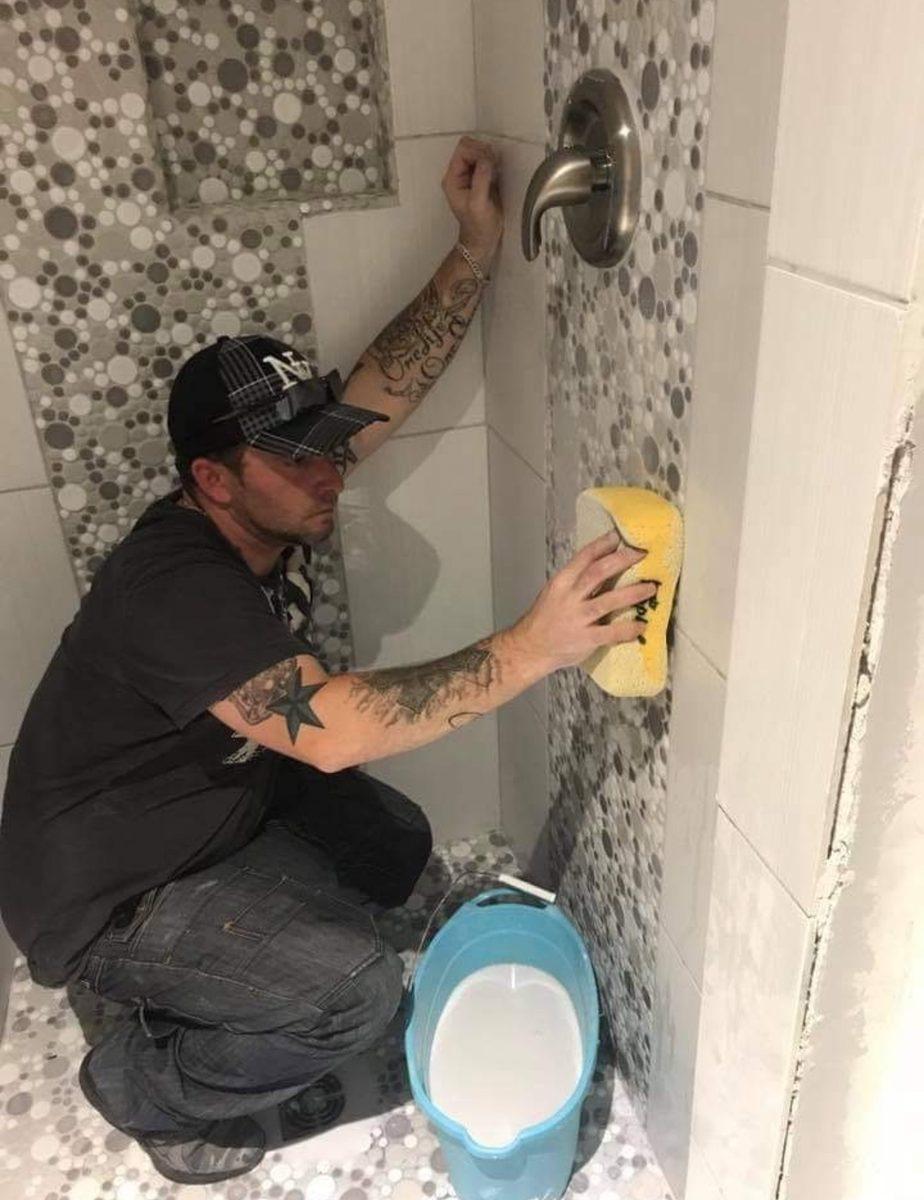 Tradesman setting wall tile around a shower valve
