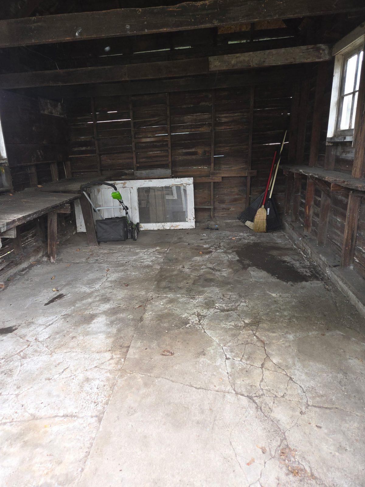 The same detached garage emptied, bare concrete floor and exposed timber walls