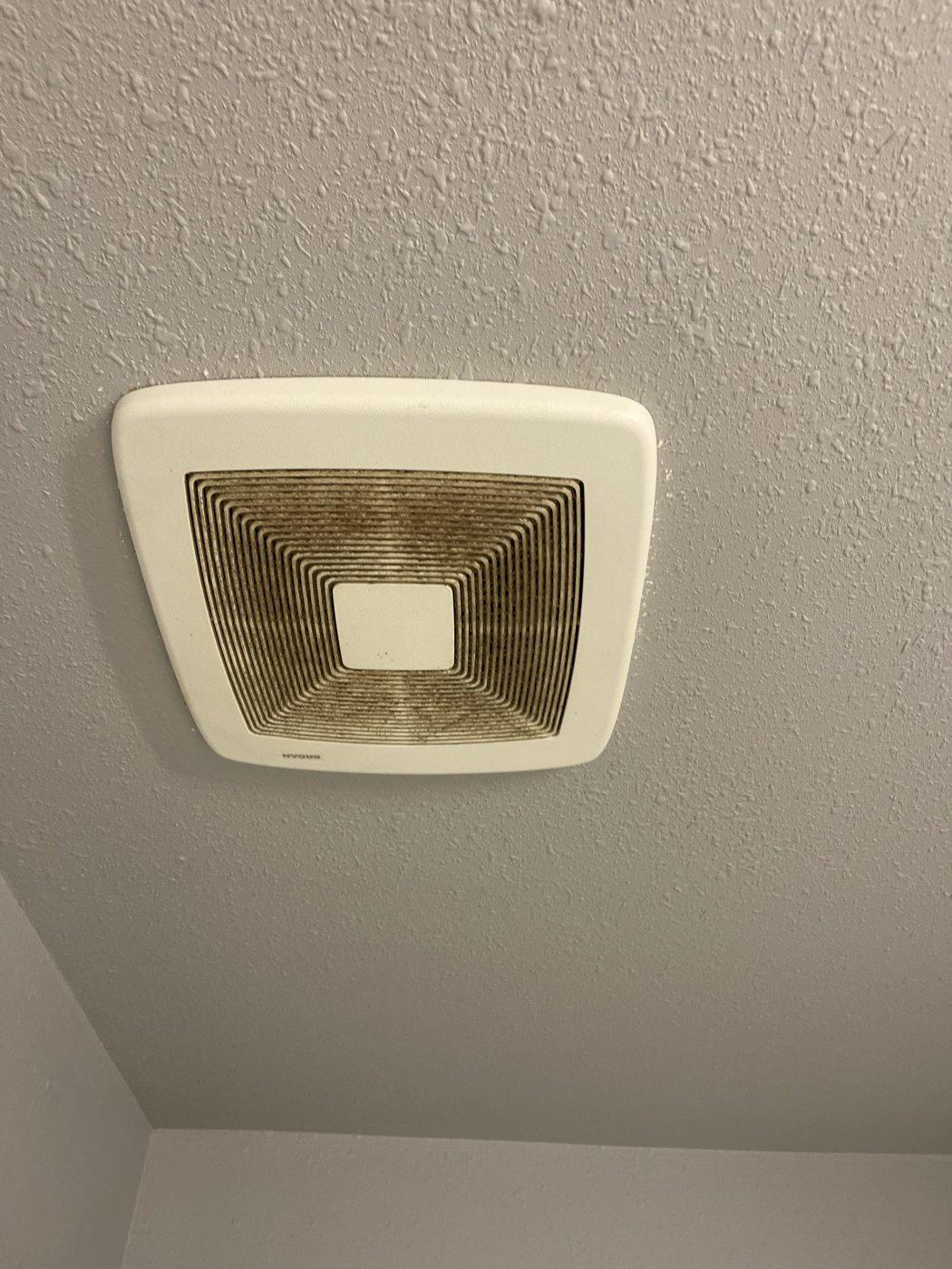 Bathroom ceiling extractor fan grille heavily discoloured with dust and moisture staining