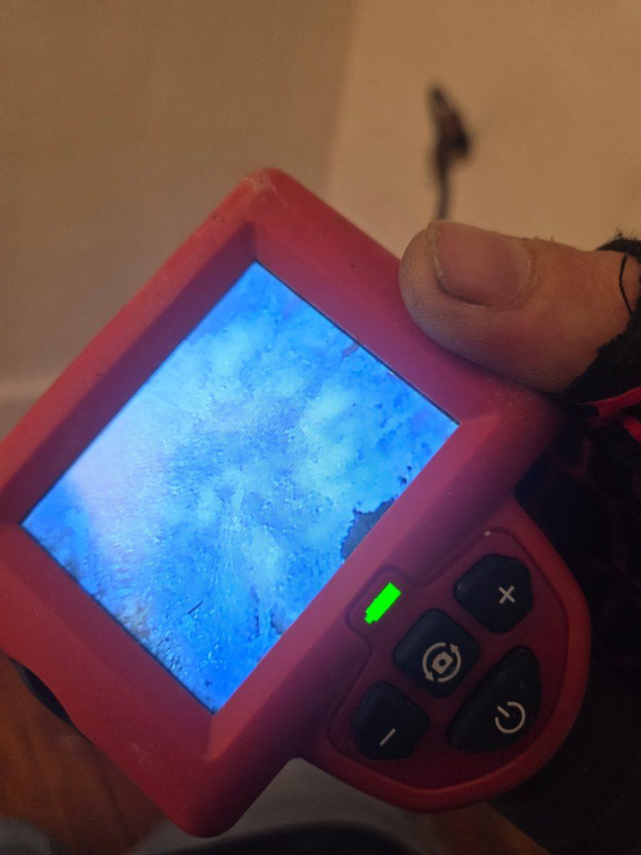Handheld inspection camera showing the inside of a wall cavity being checked for mold